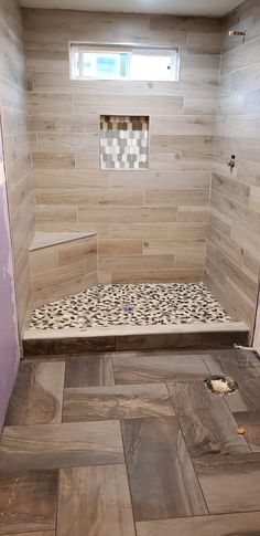 a walk in shower sitting next to a window on top of a wooden floor covered in tile