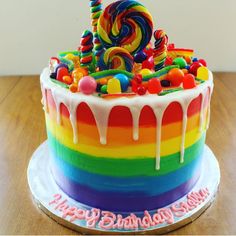 a rainbow cake with candy and lollipops on top