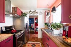 a kitchen with red cabinets and stainless steel appliances in the center, along with an area rug on the floor