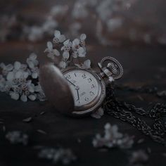 an old pocket watch with flowers on the chain and in the background it is dark