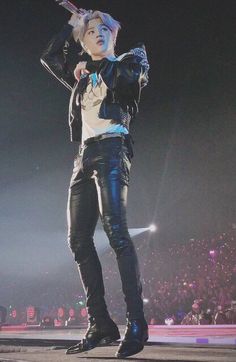 a woman standing on top of a stage with her hand up to her head and microphone in her other hand