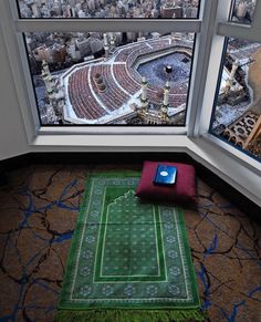 a green rug sitting on top of a floor next to a window with a view of a stadium