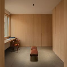 an empty room with wooden walls and a bench in the corner next to a window