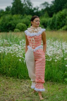 a woman in an orange and white checkered dress standing on the grass with her back to the camera