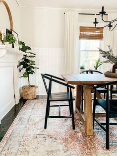 a dining room table and chairs in front of a fireplace with potted plants on it