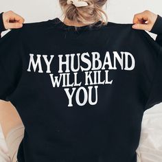 a woman with her back to the camera wearing a black shirt that says, my husband will kill you