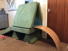 a child's bedroom with a green bed and wooden slide on the floor in front of it