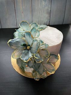 a white cake with blue flowers on top sitting on a black table next to a wooden wall