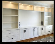 an empty room with white cabinets and drawers on the wall, along with a rug