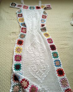 a white crocheted dress sitting on top of a bed next to a blanket