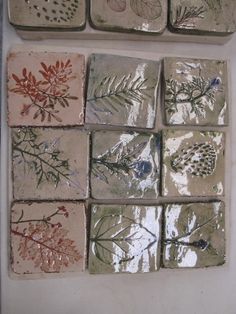 several tiles with different designs on them sitting next to each other in front of a white wall