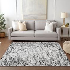 a living room with a gray couch and white rug on the hardwood floor next to a large painting