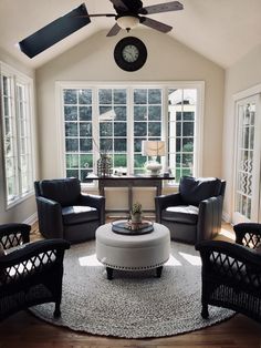 a living room filled with furniture and a clock mounted on the wall above it's windows