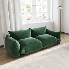 a green couch sitting on top of a hard wood floor next to a white rug