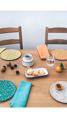 a wooden table topped with plates and bowls filled with food next to an orange slice