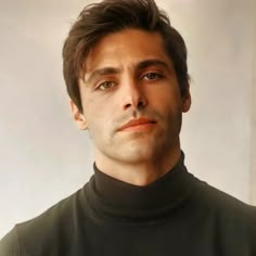 a man in a black turtle neck shirt looking at the camera with a serious look on his face