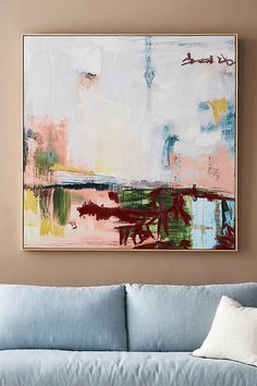 an abstract painting hangs on the wall above a blue couch