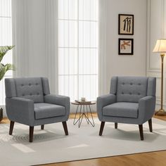 two gray chairs sitting next to each other on a rug in front of a window