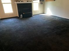 an empty living room with a fireplace in the corner