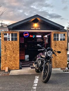 a motorcycle is parked in front of a small building that has a bar on it