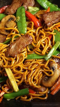 stir fry with meat, vegetables and noodles in a wok on the stove top