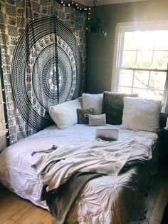 an unmade bed in front of a window with lights hanging from the windowsill