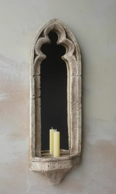 a candle that is sitting in front of a mirror on the side of a wall