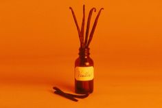 a bottle with sticks sticking out of it sitting on an orange surface next to a black object