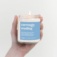 a hand holding a candle that reads currently reading