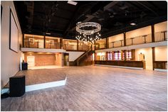 an empty dance floor with chandelier hanging from the ceiling and lights above it