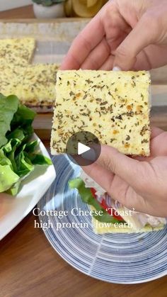 two hands holding pieces of food over a plate with lettuce and cheese on it