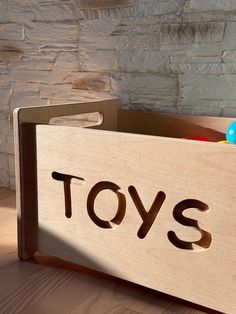 a wooden toy box with toys in it on a table next to a brick wall