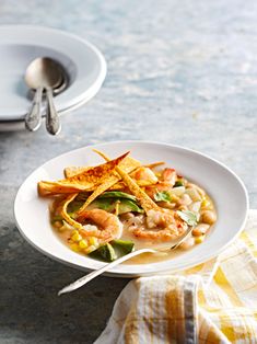 a white bowl filled with food on top of a table next to a fork and spoon