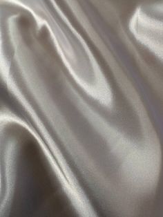 a close up view of a white satin fabric with very soft folds and wrinkles