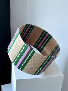 a close up of a wooden object on top of a white block with pink and green stripes