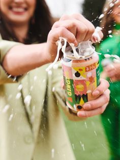 a woman is sprinkled with white powder on her hand and holding a can