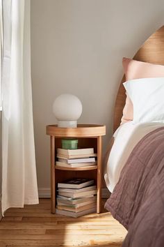 a bed room with a neatly made bed and a night stand next to the window