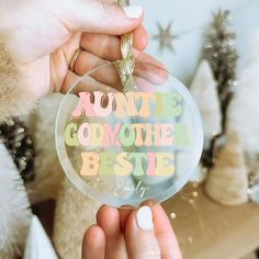 a person holding up a glass ornament with the words'auntie godmoter bestie '