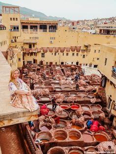 a woman sitting on top of a roof next to lots of potted planters