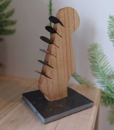 a wooden sculpture with several knives sticking out of it's back end on top of a table