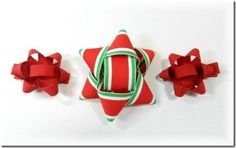 three red and green bows are attached to a star shaped ornament on a white surface