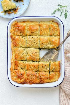 a casserole dish filled with bread and topped with sesame seeds, sits on a white surface