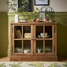 a wooden cabinet with glass doors and plants on top