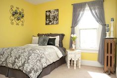 a bedroom with yellow walls and white carpeted flooring has a large bed in it