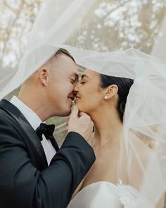 a bride and groom kissing under a veil