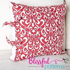 a red and white pillow sitting on top of a bed next to a white headboard