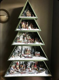 a christmas tree made out of wooden shelves filled with small houses and snow covered trees