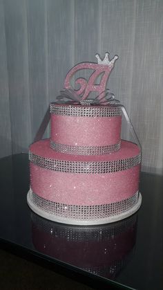 a three tiered cake with pink frosting and bling on the top layer