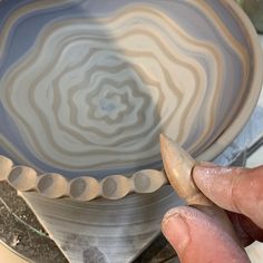 a person is painting a bowl with acrylic paint and wood shavings