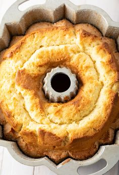 a bundt cake in a metal pan on a white wooden table with a hole in the middle